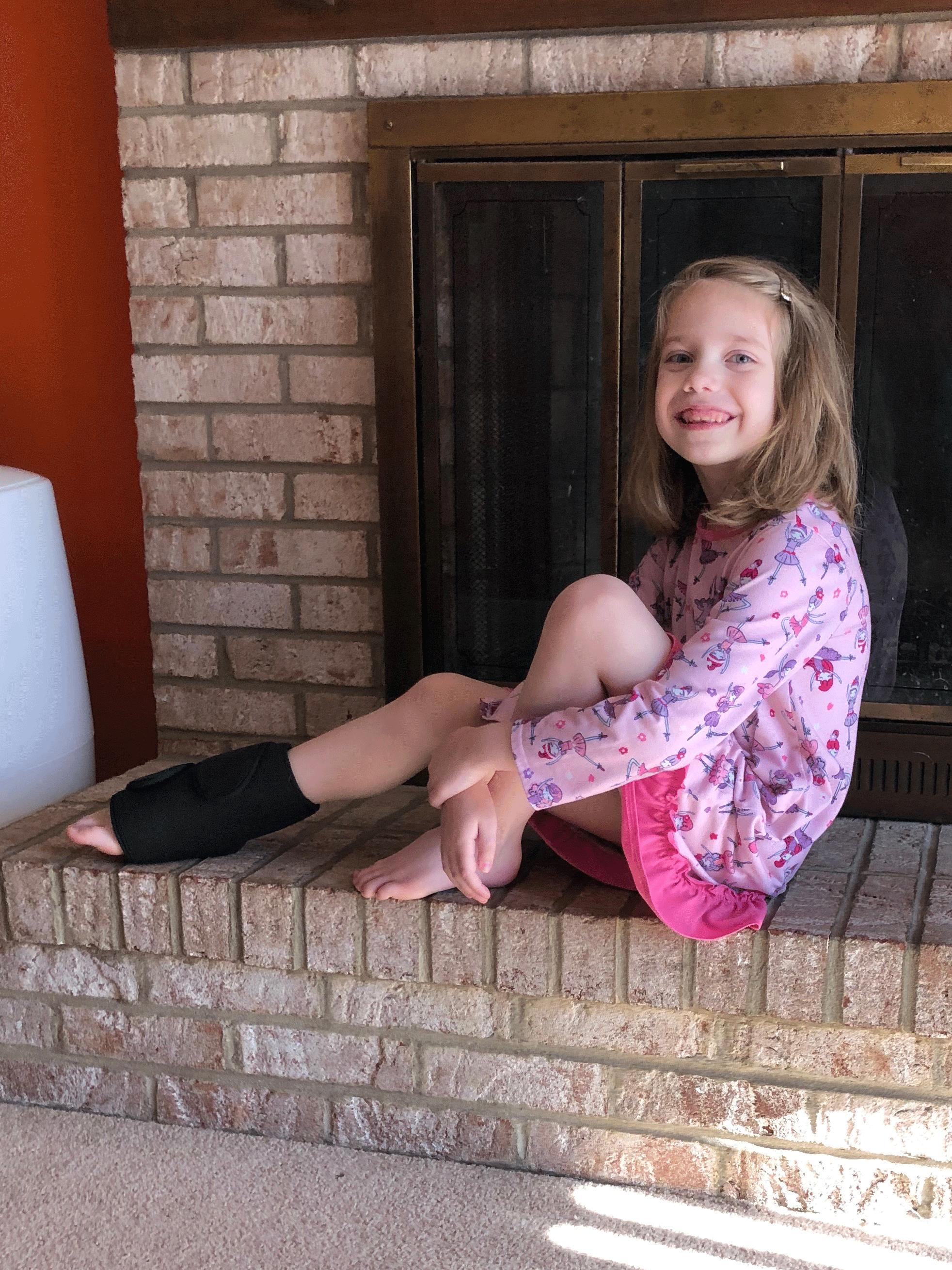 A girl sitting on the ground with a soft ice wrap on her foot