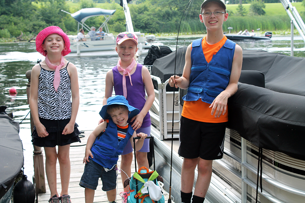 Four kids at a river wearing Cool Kids cooling vests and cooling neck wraps