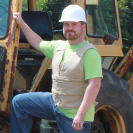 Man wearing khaki kool max adjustable zipper front cooling vest in front of construction equipment