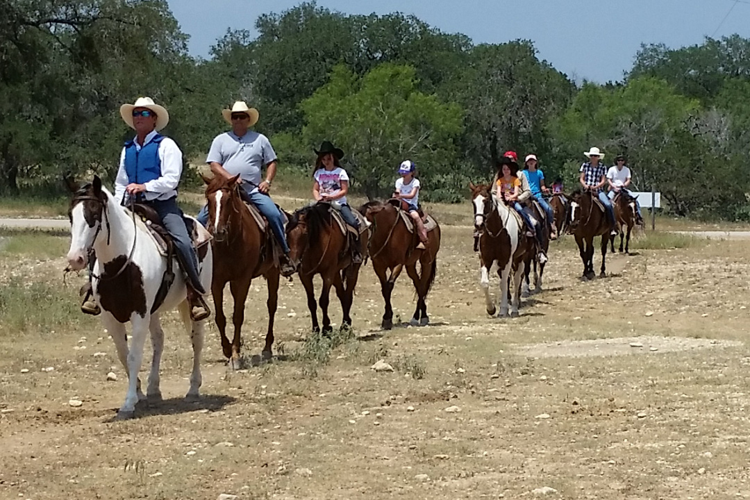 Man wearing a Cool58 phase change cooling vest on horseback while leading a group of people on horses