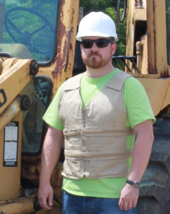 Man wearing khaki kool max adjustable zipper front cooling vest in front of construction equipment