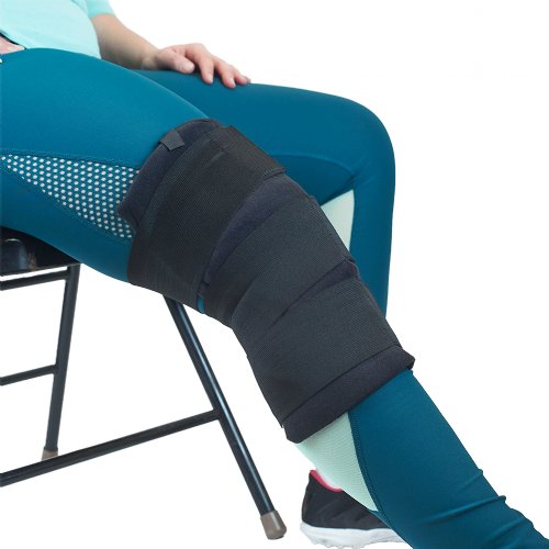 A woman is shown sitting down wearing a Soft Ice Knee wrap 