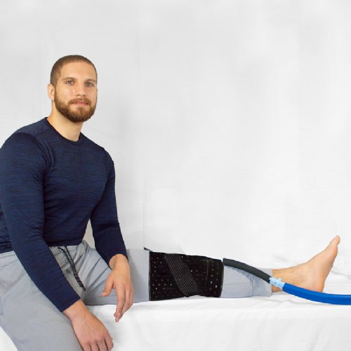 an athletic man hooked up to a full circumference cold water knee system 