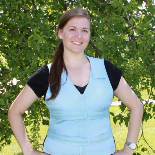 Young woman standing against a tree wearing a light blue adjustable cooling vest
