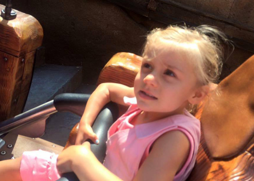 Girl in pink kool max toddler cooling vest on an amusement park ride